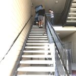 Professional piano movers moving a protected piano up an exterior staircase in Utah